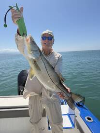 An angler proudly displaying a large Snook while fishing on a sunny day, showcasing the excitement of a successful catch.