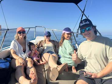 A family enjoying a relaxing day on a boat, with a child and several adults seated comfortably, surrounded by calm waters.