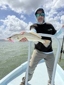 Angler proudly displaying a Speckled Trout while fishing on a sunny day, showcasing the excitement of a successful catch.