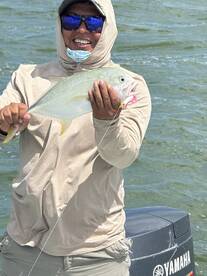 Angler proudly displaying a vibrant fish while fishing on a sunny day, showcasing a successful catch.
