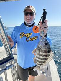 Angler proudly displaying a large Black Sea Bass while fishing on a sunny day.
