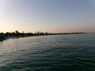 A serene view of the waterfront at dusk, showcasing the calm waters and surrounding buildings, ideal for fishing charters.