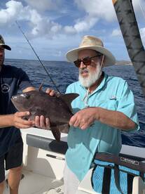 Two anglers proudly displaying a large fish while fishing in open waters, showcasing a successful day on the boat.