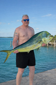 An angler proudly displaying a vibrant Mahi Mahi at the dock, showcasing a successful fishing trip.