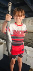Young angler proudly holding a fish while fishing from a boat, showcasing a fun day on the water.