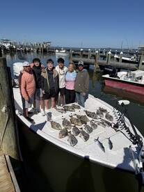 A family group proudly displaying their catch of various fish on a boat after a successful fishing trip.
