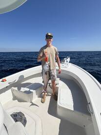 Angler proudly displaying a large fish on a boat during a deep-sea fishing trip.