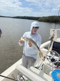 Angler holding a Snook while fishing in a scenic estuary, showcasing a successful catch during a relaxing day on the water.