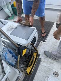 A fisherman is preparing a freshly caught fish on a boat, showcasing the catch in a lively fishing environment.