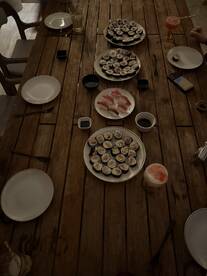 A dining table set with various sushi plates and drinks, showcasing a social dining experience.