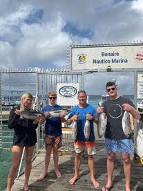 A family proudly displaying their catch of Yellowfin Tuna at Bonaire Nautico Marina after a successful fishing trip.