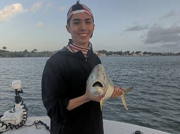 Young angler proudly holding a large fish while on a boat, showcasing a successful fishing trip.
