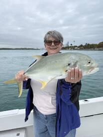 A proud angler holding a large Jack Crevalle while enjoying a fishing trip on the water.