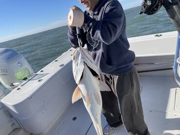 Angler proudly displaying a large fish on a boat during a fishing trip.