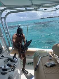 A snorkeler preparing to dive off a boat in clear turquoise waters, showcasing the boat's interior and equipment.