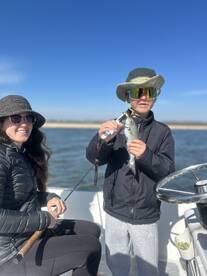 A young angler proudly displaying a caught fish while fishing with a family member on a sunny day.