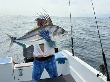 Angler proudly displaying a large fish while aboard a boat, showcasing a successful day of fishing in open waters.