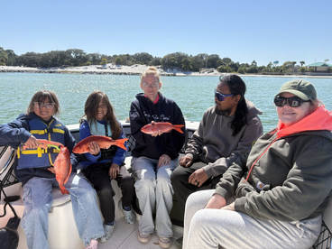 A family proudly displaying their catch of red snapper while enjoying a sunny day on the water.