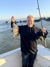 Angler proudly displaying a freshly caught Black Drum while fishing from a boat in coastal waters.