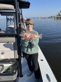A smiling angler proudly displays a freshly caught Redfish while enjoying a day on the water.