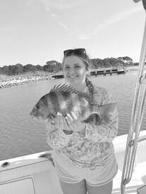 A young angler proudly displaying a large Snapper while fishing from a boat, showcasing a successful day on the water.