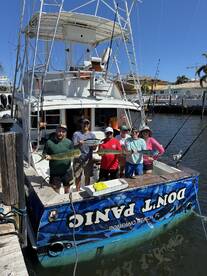 A group of anglers proudly displaying their catch of Mahi Mahi in front of the 'Don't Panic' charter boat in Pompano Beach, FL.