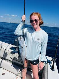 A proud angler holding a beautiful fish while fishing on a sunny day, showcasing a successful catch in a vibrant marine environment.