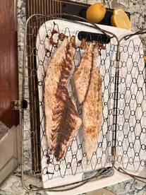 Two seasoned fish fillets displayed on a grill rack, accompanied by a lemon, ready for cooking.