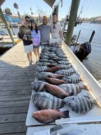 A group of anglers proudly displaying a variety of fish, including snapper and grouper, arranged neatly on a catch board at the dock.