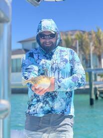 Angler proudly displaying a colorful Pufferfish while enjoying a sunny day on the water.