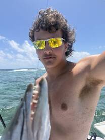 A young angler proudly displaying a fish while enjoying a sunny day on the water.