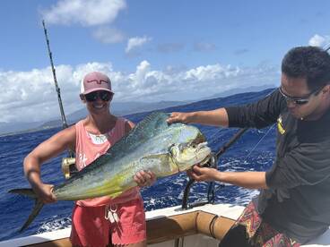 A smiling angler proudly displays a large Mahi Mahi while fishing offshore, showcasing the excitement of a successful catch.