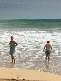 A woman and a child enjoying the beach, playing in the waves on a sunny day.
