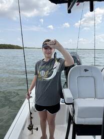A young angler proudly displaying a small fish while fishing on a boat, enjoying a day on the water.