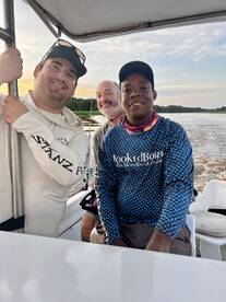 Three anglers enjoying a scenic boat ride on a river, showcasing camaraderie and the fishing experience.