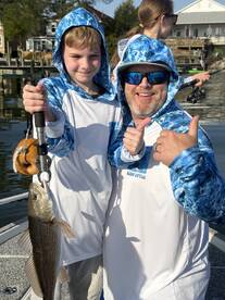 A young angler and an adult proudly displaying a caught fish while enjoying a day of fishing together.
