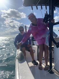 Two anglers enjoying a sunny day on the water, proudly displaying a caught shark while aboard a fishing boat.