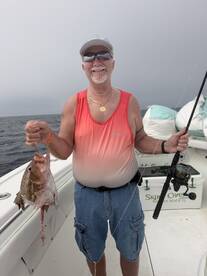 An angler proudly displaying a freshly caught fish while fishing on a charter boat in the open sea.