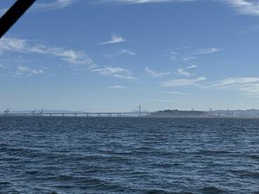 A scenic view of a bridge and distant land from the boat, showcasing the beautiful coastal environment.