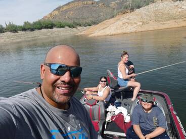 A joyful family fishing together on a boat, enjoying a sunny day at the lake.