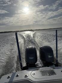 A scenic view from the back of a boat with twin Yamaha 300 engines, showcasing a sunny day on the water.