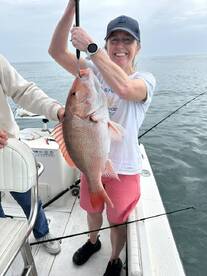 A proud angler holding a large Snapper while fishing on a boat, showcasing a successful day on the water.