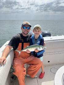 A proud father and son duo displaying a freshly caught fish while enjoying a day on the water.