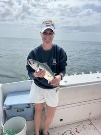 Angler proudly displaying a freshly caught fish on a boat in open water, showcasing a successful fishing trip.