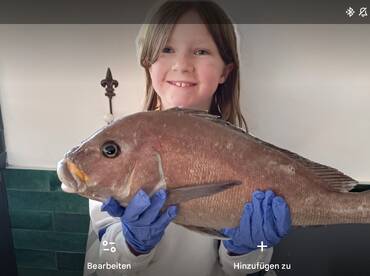 A young angler proudly displaying a large Snapper, showcasing a successful fishing trip.
