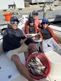 A family proudly displays their catch of the day, featuring several fish, while enjoying a fishing trip on a boat.