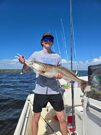 A young angler proudly displaying a large Redfish while fishing on a sunny day.