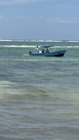 A small fishing boat navigating through clear waters, with a group of anglers onboard enjoying a day of fishing.