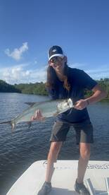 Young angler proudly displaying a Tarpon while fishing in a scenic coastal environment.