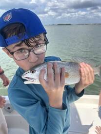 A young angler proudly holding a Redfish while enjoying a day out on the water.